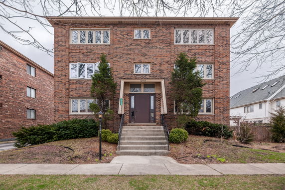 Front view of a brick apartment building with multiple windows and a central entrance.