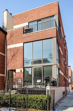 Front view of a modern brick multi-story building with large windows and balconies.
