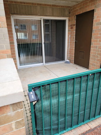 Front view of a brick building with sliding glass doors and a small patio area.