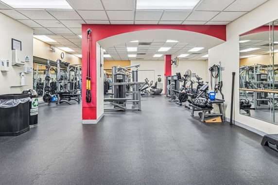 Spacious gym area with various exercise equipment and mirrored walls.