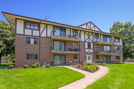 Front view of a multi-story residential building with balconies and brick facade.