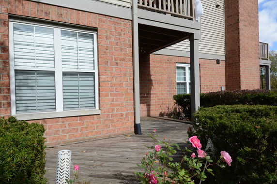 Partial view of a brick house with a balcony and windows.
