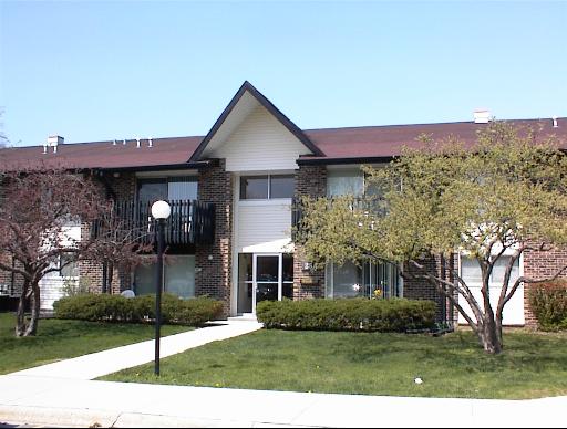 Front view of a two-story brick apartment building with a pitched roof and central entrance.