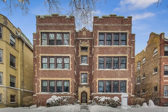 Front view of a three-story brick building with multiple windows and a decorative entrance.