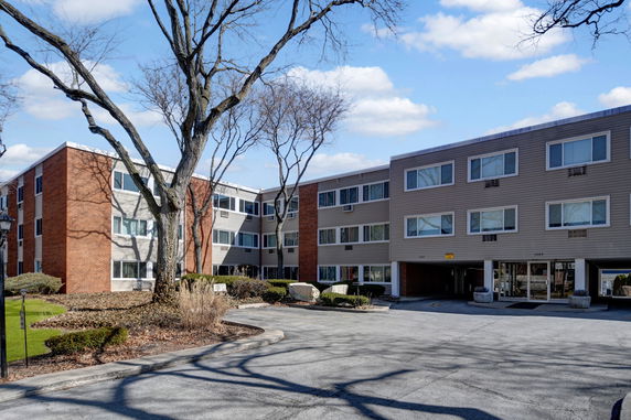 Front view of a three-story apartment building with a mix of brick and siding exterior.
