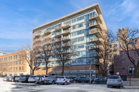 Front view of a multi-story apartment building with balconies and large windows.