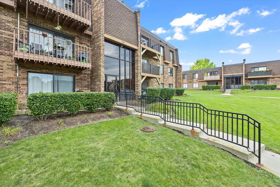 Front view of a multi-story brick apartment building with balconies and large windows.