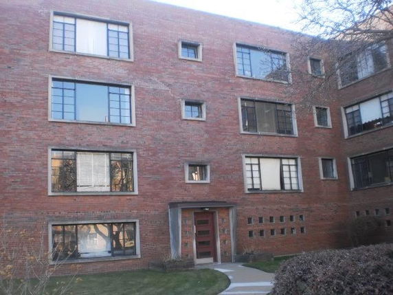 Front view of a brick apartment building with multiple large windows.