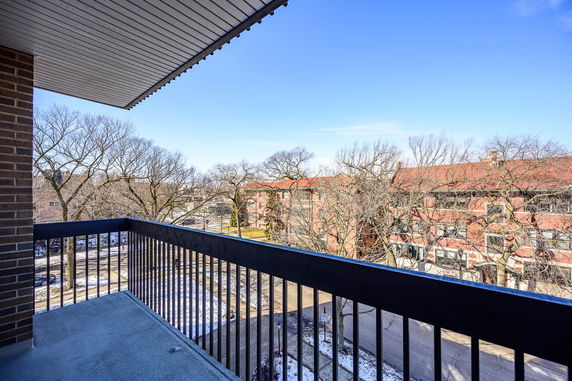 Panoramic view from a balcony overlooking tree-lined street and buildings.