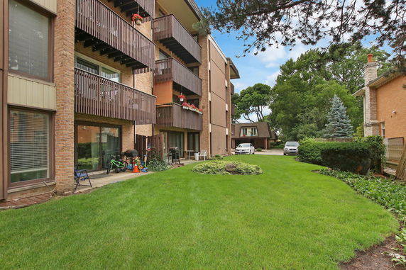 Front view of a multi-story building with balconies and a grassy lawn.