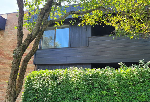 Front view of a two-story building with a brick facade and dark panel siding.
