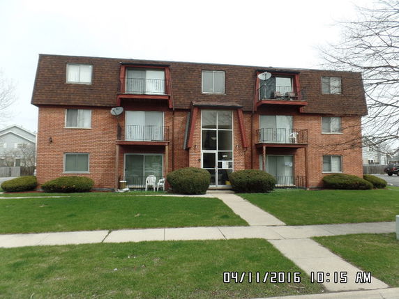 Front view of a multi-story brick apartment building with balconies.