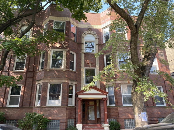 Front view of a multi-story brick building with bay windows.