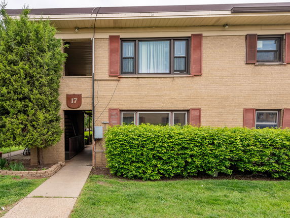Front view of a two-story brick apartment building with entryway and staircase.