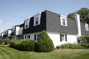 Front view of a two-story house with a dark roof and white walls.
