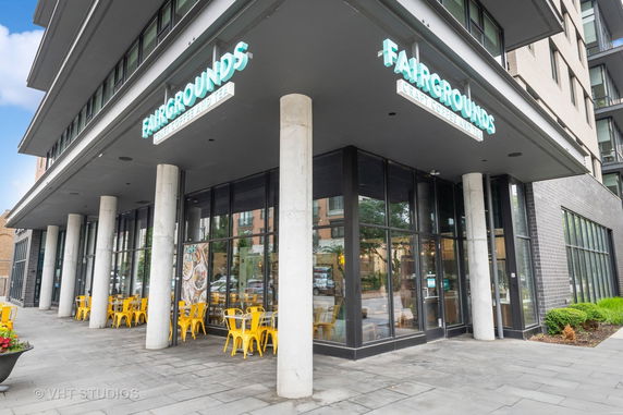 Front view of a modern building with glass windows and a sidewalk cafe area.