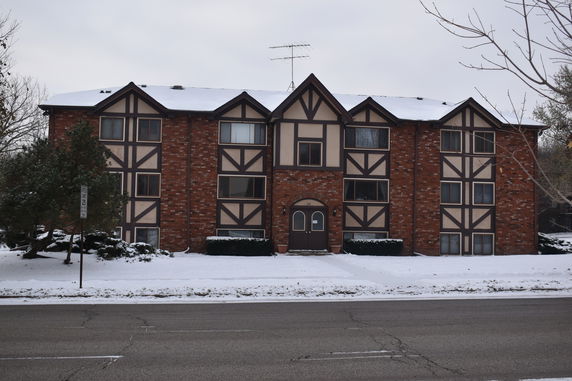 Front view of a two-story brick apartment building with triangular roof structures.