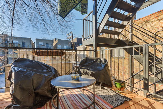 Rooftop patio area with chairs, a table, and metal stairs.