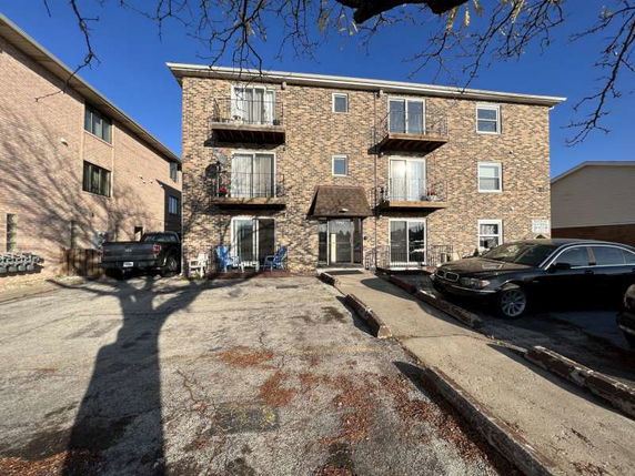 Front view of a three-story brick apartment building with balconies.