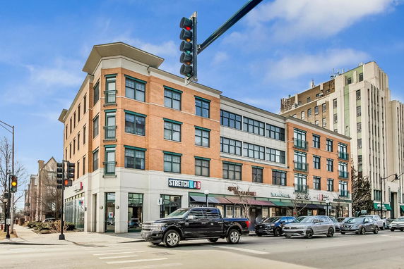 Front view of a multi-story mixed-use building with retail stores on the ground level.