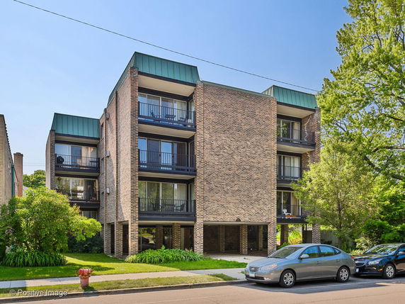 Front view of a three-story brick apartment building with balconies.