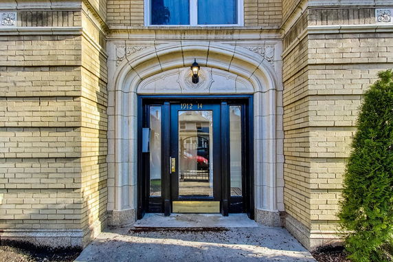 Front view of a building entrance with decorative brickwork and glass doors.