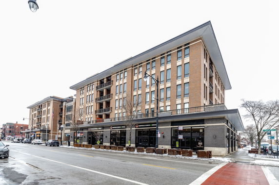 Front view of a multi-story building with brick façade and commercial spaces on the ground floor.