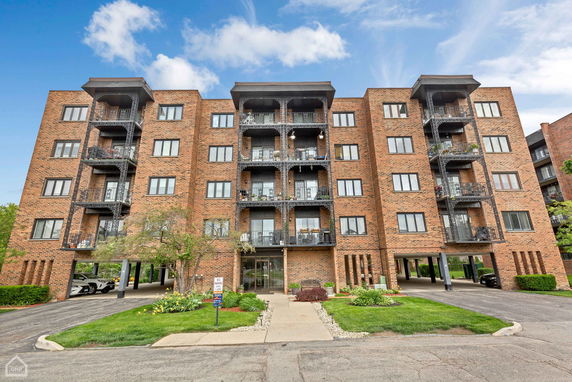 Front view of a multi-story brick apartment building with balconies.