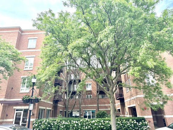Front view of a multi-story brick apartment building with balconies and large windows.