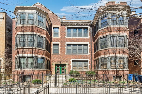 Front view of a multi-story brick building with large bay windows.