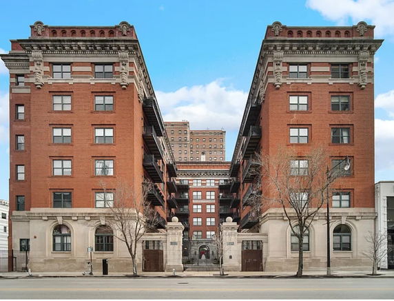 Front view of a multi-story red brick apartment building with ornamental architectural details.