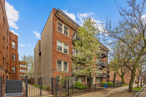 Front view of a multi-story brick apartment building with balconies.