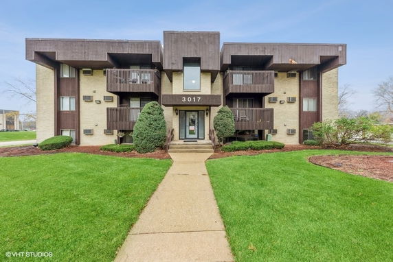 Front view of a multi-story apartment building with balconies and central entrance.