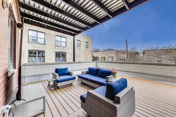 Rooftop patio with outdoor seating and view of neighboring buildings.