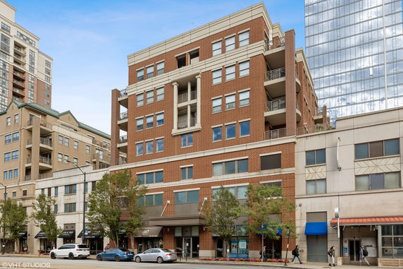 Front view of a multi-story brick building with balconies and large windows.