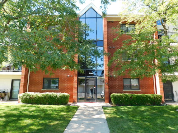 Front view of a multi-story brick building with large glass windows.