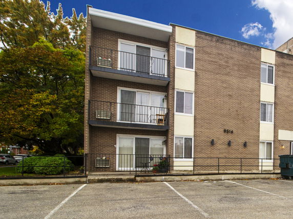 Front view of a three-story apartment building with balconies.