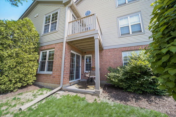 Front view of a multi-story house with a small balcony and patio area.