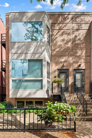 Front view of a modern multi-story house with large windows and brick facade.