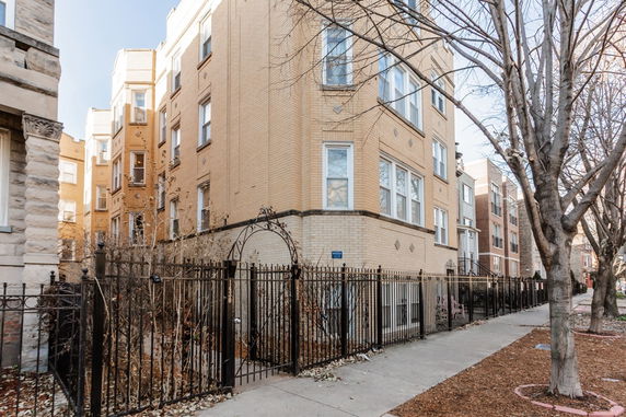 Front view of a multi-story brick building with a fenced yard.