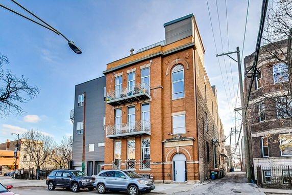Front view of a multi-story brick building with balconies and large windows.