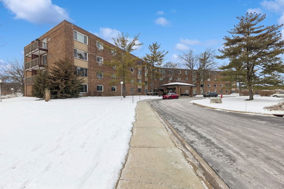 Front view of a multi-story brick building with snow on the ground.