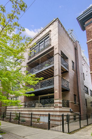 Front view of a multi-story residential building with balconies and a brick facade.