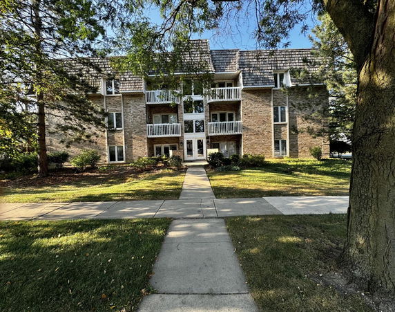 Front view of a three-story brick residential building with balconies.