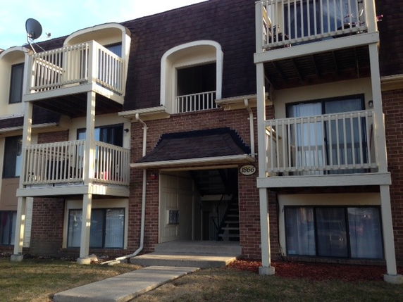 Front view of a multi-story apartment building with balconies and an entrance.