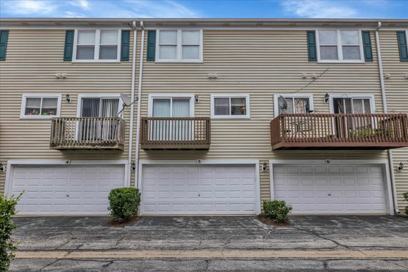 Front view of a multi-story townhouse with garage and balconies.