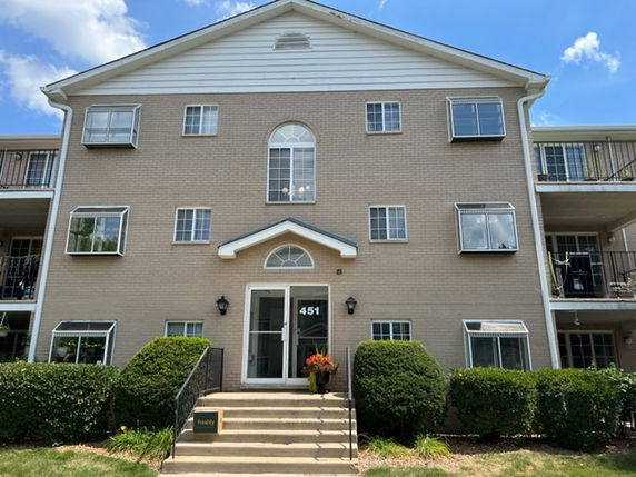 Front view of a multi-story residential building with a brick exterior and multiple balconies.