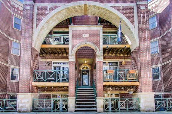 Front view of a multi-story brick building with archways and balconies.