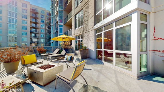 Rooftop patio with lounge chairs, umbrellas, and a fire pit area.