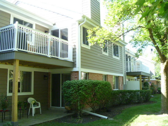 Side view of a two-story house with balconies and wooden siding.